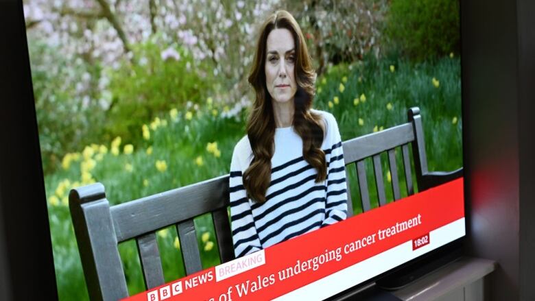 A television shows a person sitting on a bench in a garden.