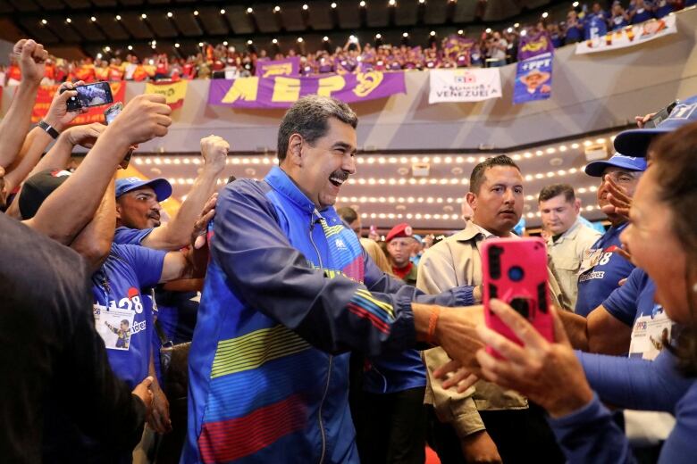 A person shakes hands with supporters during a political rally.