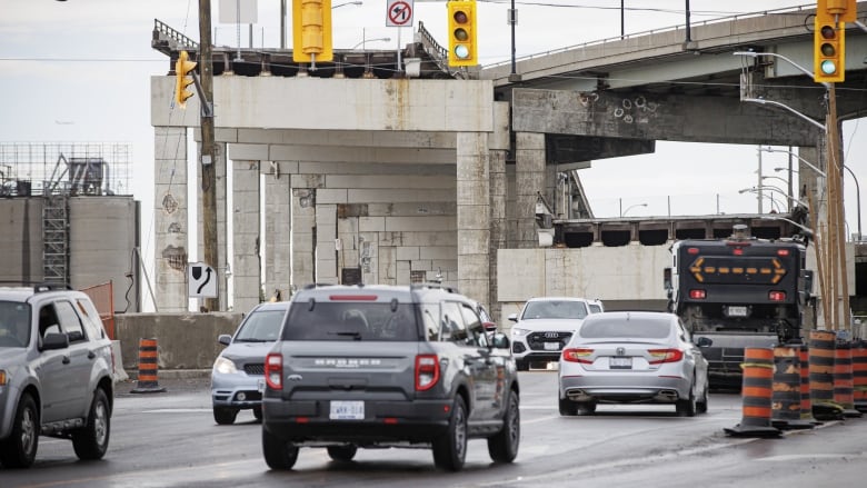 Vehicles drive on Lake Shore Boulevard East in Toronto, with the Gardiner Expressway in view overhead. 