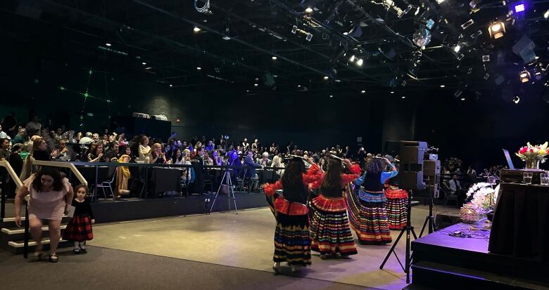 A group of dancers performs in front of an audience.