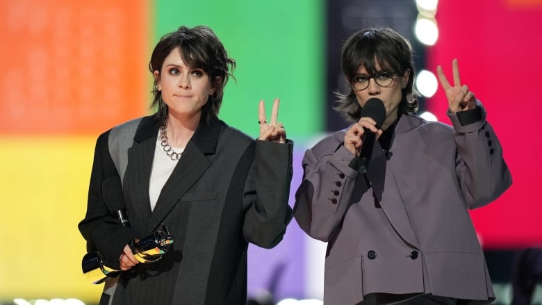 Two women stand on a stage.