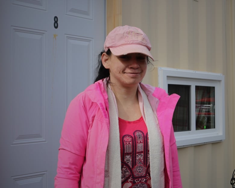 A woman in a bring pink jacket and a pink baseball hat. 