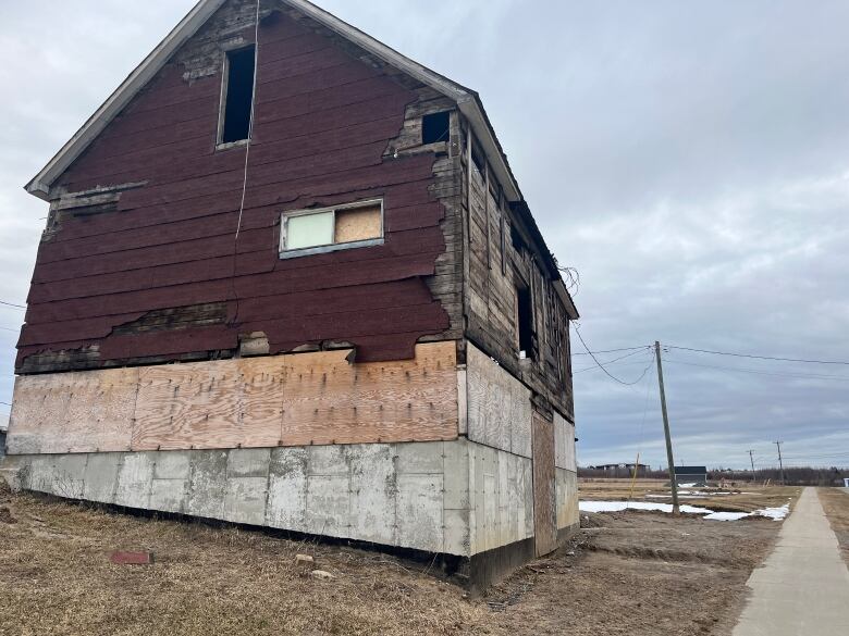 An old barn in need of repair next to a sidewalk