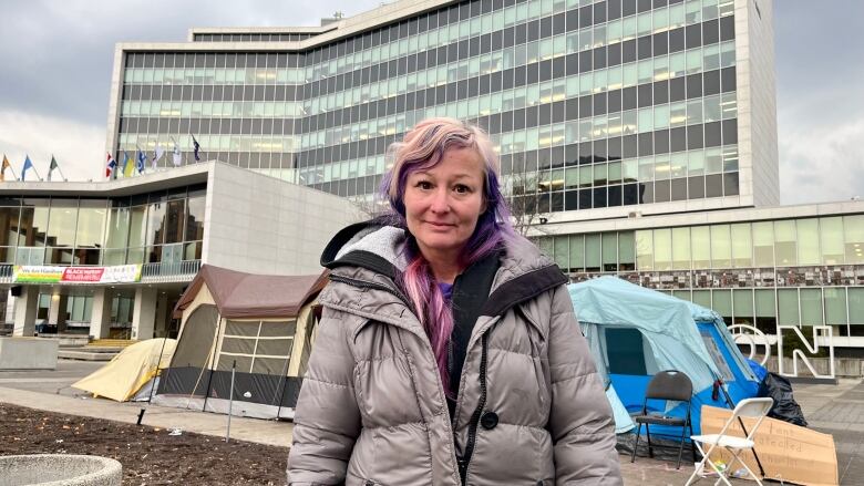 Woman stands in front of tent and municipal building