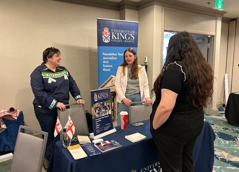 a booth with university advertisements presenting to a youth.