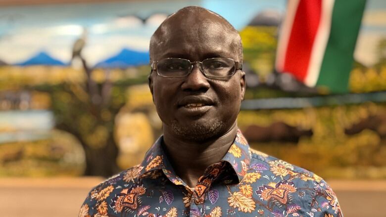 A man in glasses and a patterned shirt poses for the camera.