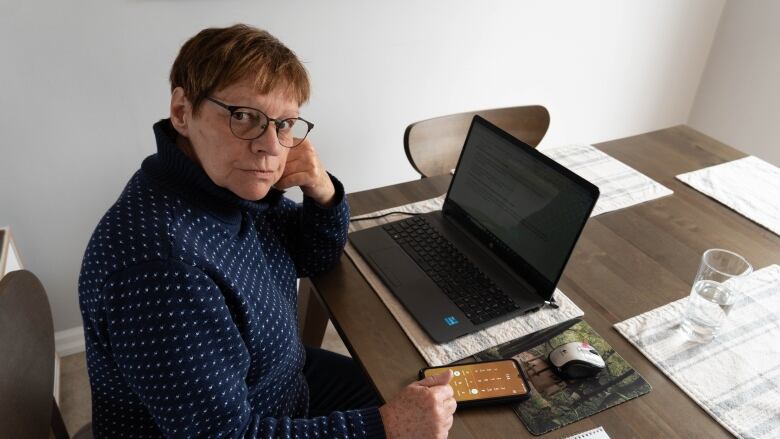 A woman sits in front of a laptop.