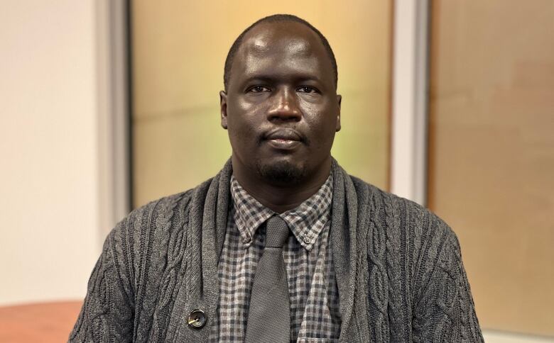 A portrait of a man in a cardigan sweater and tie.