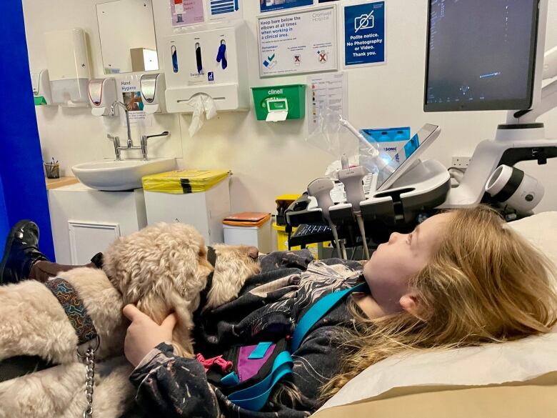 A young girl lying down with a dog beside her.