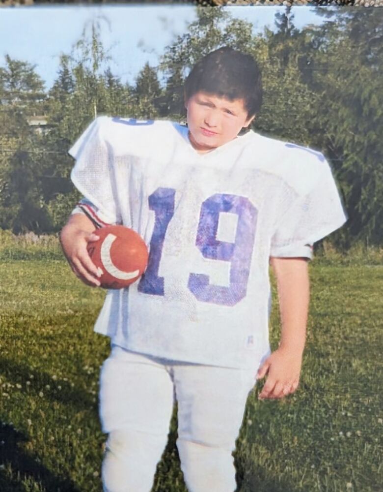 young teen boy standing in a sports uniform, posing for photos.