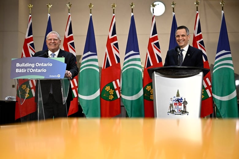 A premier and a mayor smile during a news conference.