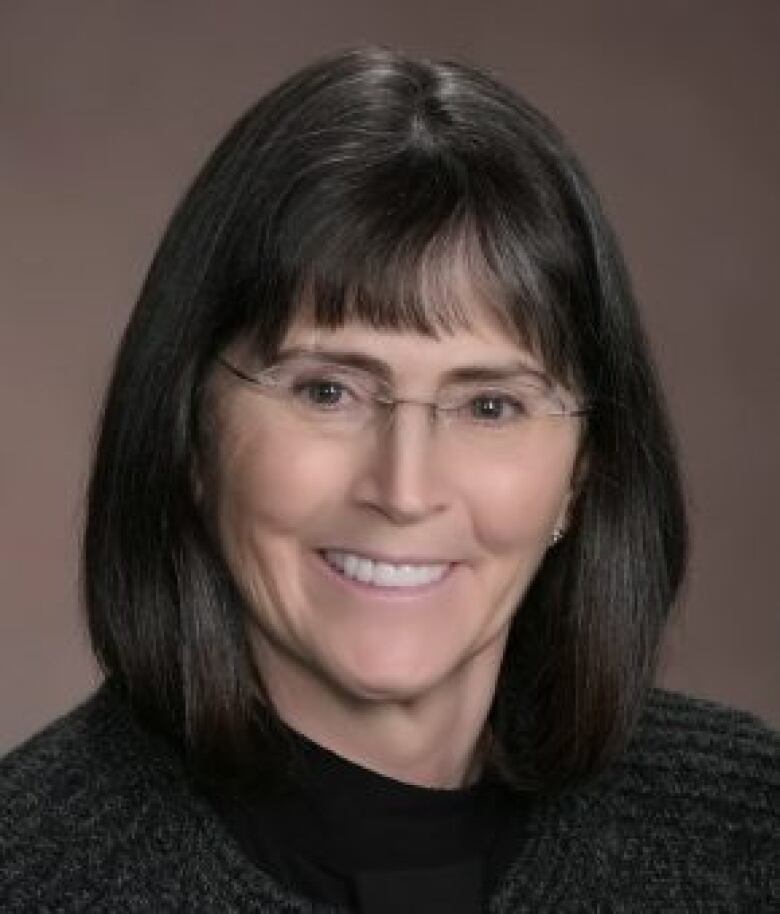 A smiling woman with a short black bob with bangs.