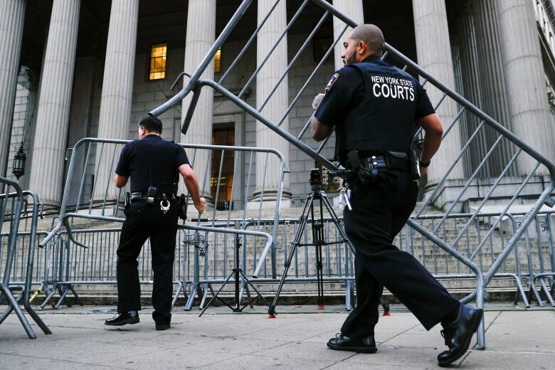 Police set up metal barriers outside columned building