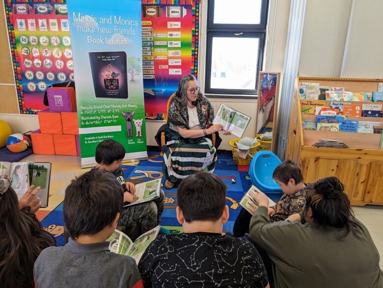 A woman reads a book to a classroom of children