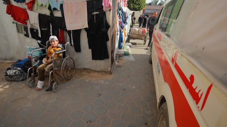 Nine year old Yahya Hamad waits in a wheelchair beside the ambulance that will take him out of Gaza.