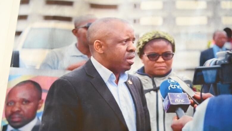 Frederick Mwenengabo speaking to a microphone