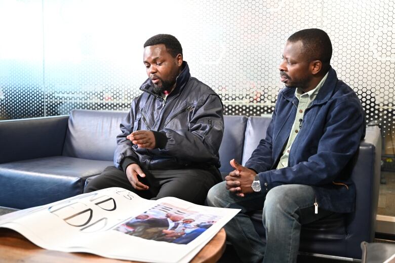 Lundi Karhibahaza, left, and Simon Chinamula, right with poster