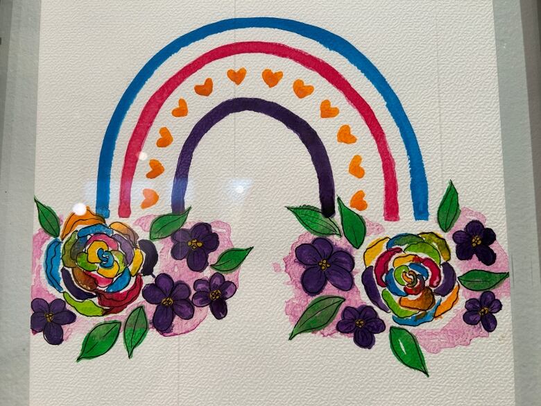 A colourful painting of a rainbow with flowers at each end.