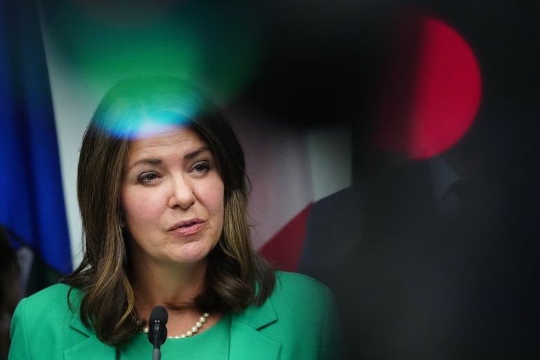 A woman in a green suit wearing a pearl necklace.