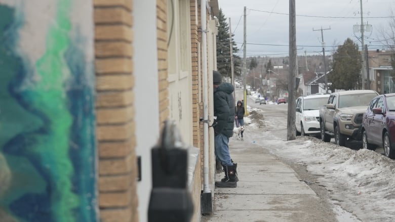 A man enters a building on a snowy, busy street downtown Timmins.