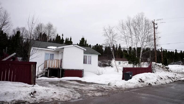 A white home is surrounded by a red fence. 