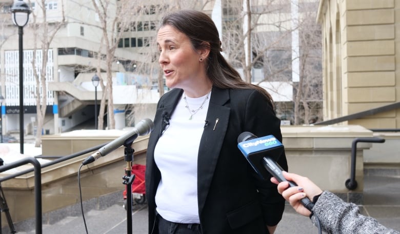 A woman wears a blazer in front of a microphone.