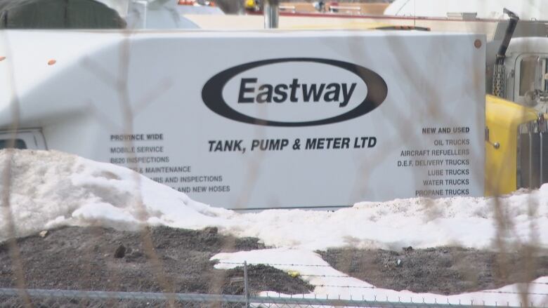 A sign for Eastway tank through a fence in winter.