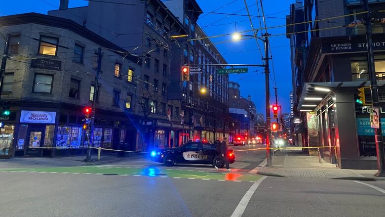 A flashing police vehicle sits parked in front of an intersection.