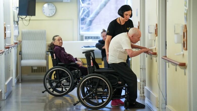 A health-care worker helps an elderly man do strength exercises.