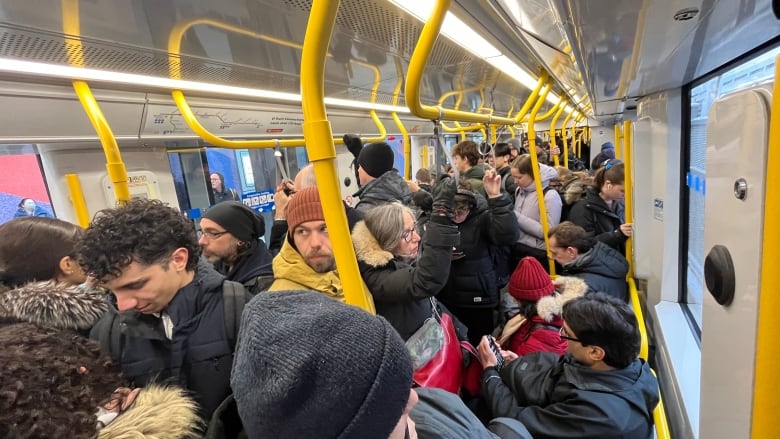 Inside a full public transit train on a snowy spring morning.