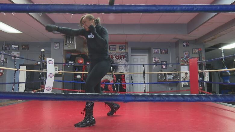 A teenage female boxer trains in a ring.