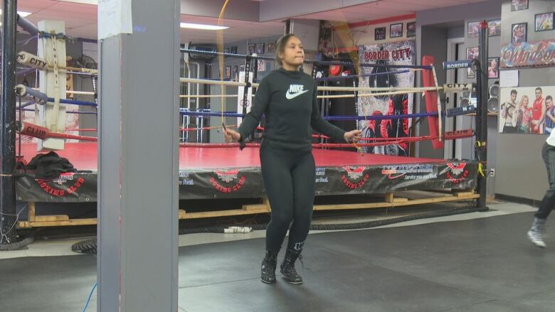 A teenage female boxer warms up with a jump rope.