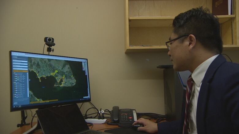 A man looking at a map on a desktop computer 