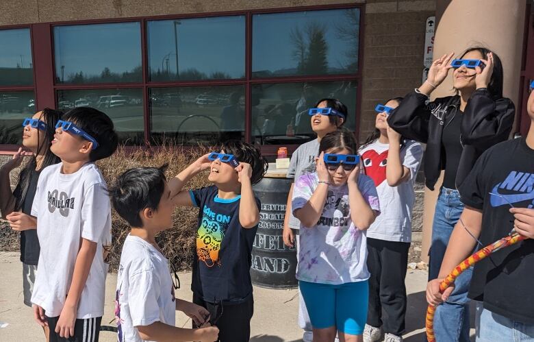 A group of students look to the sky. 