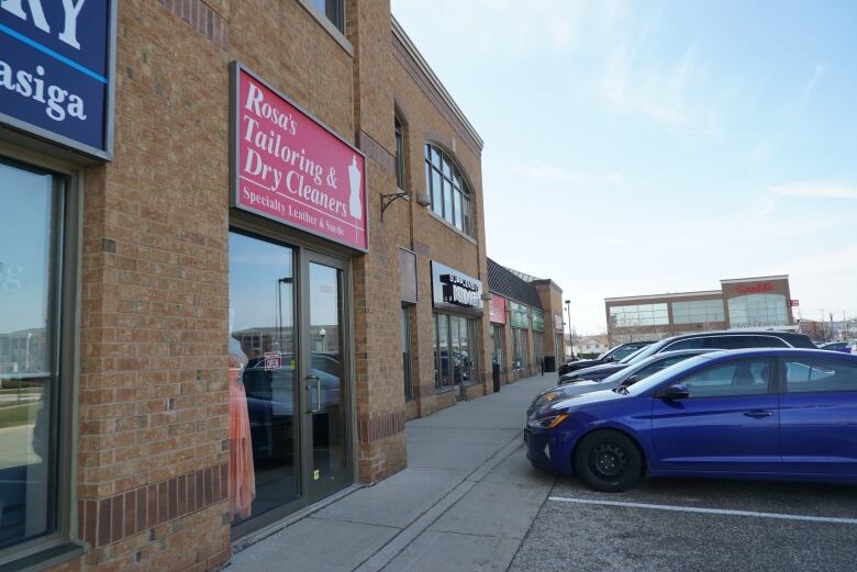 The outside of a store. A red sign sits above a door.