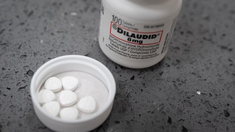 a white pharmacy bottle with cap lying upside down with some pills in it