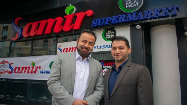 Two men standing in front of a store.