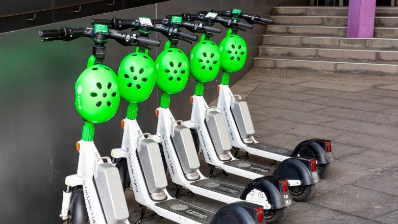 Five Lime e-scooters are pictured in front of a building.