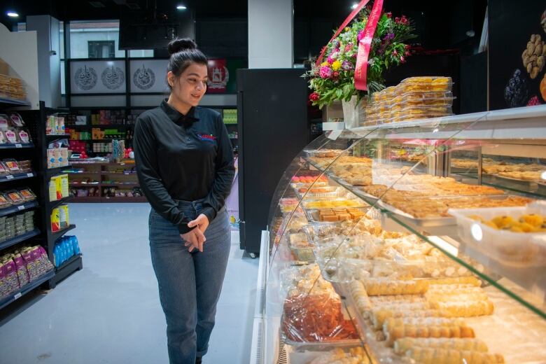 A woman standing beside a display counter with sweets.