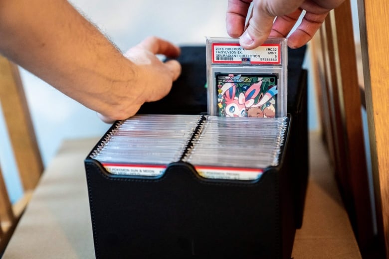 A close up of a hand pulling a graded Pokemon Card out of a box.