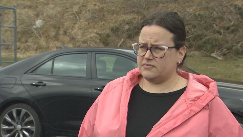 A woman stands near a black car.