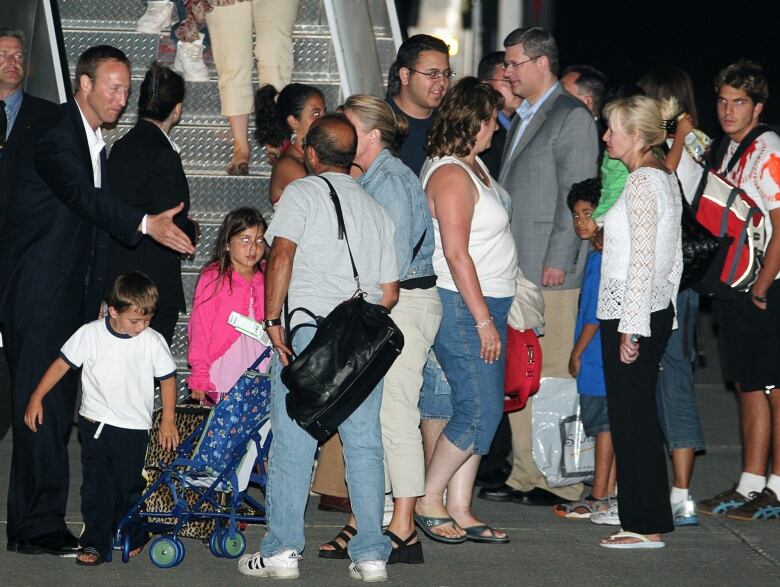 Prime Minister Stephen Harper along with his Laureen (right) and Foreign Affairs Minister Peter MacKay (left) greet evacuees from Lebanon as they disembark Harper's aircraft after arriving in Ottawa early Friday, July 21, 2006. 