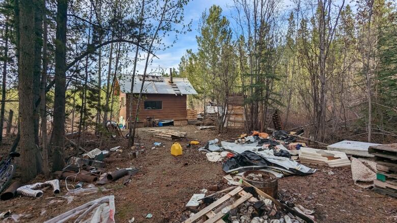 A cabin is surrounded by garbage.