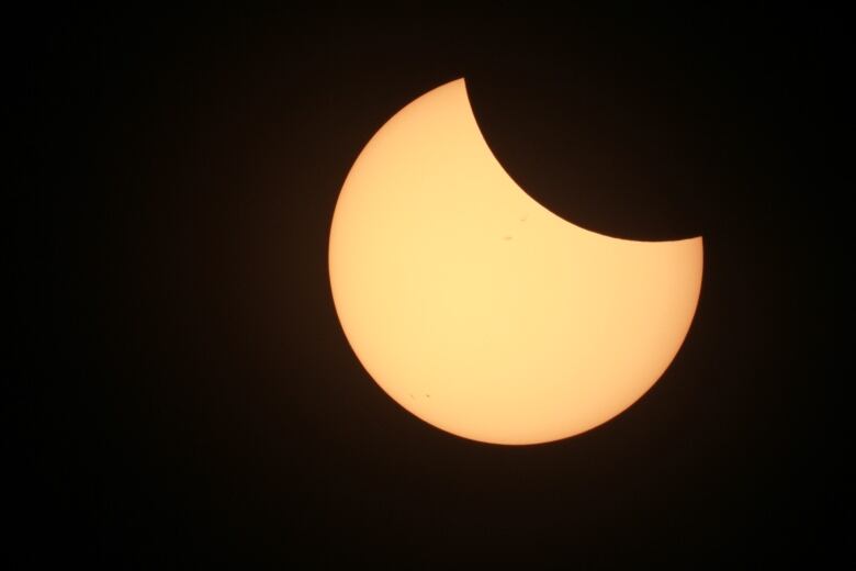 A sun partially blacked out against a dark sky. 