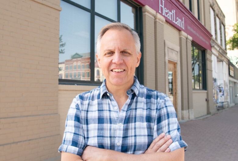 A man standing in front of a building with his arms crossed.