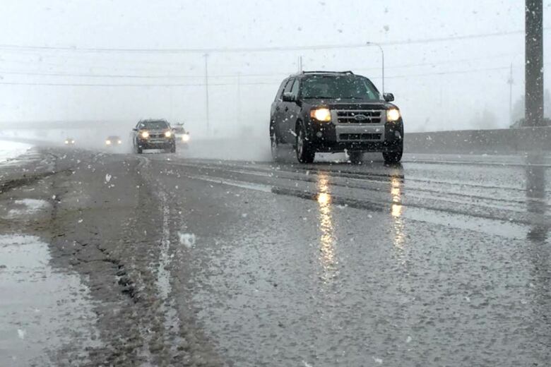 a snowy road. cars are driving past.