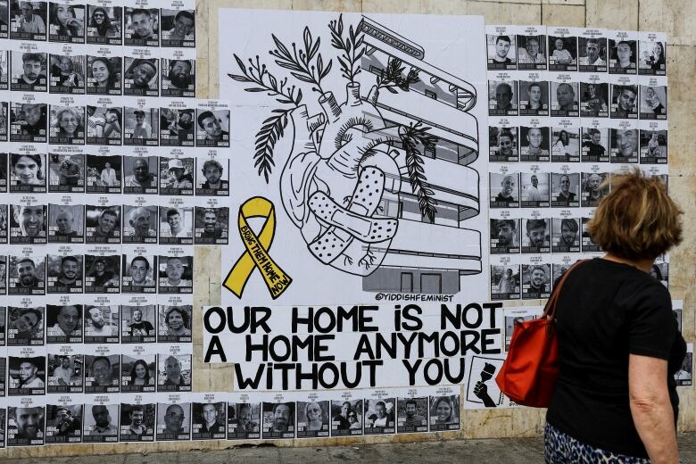 A woman looks at a wall of pictures of people surrounding a poster with the words 'Our home is not a home anymore without you.'