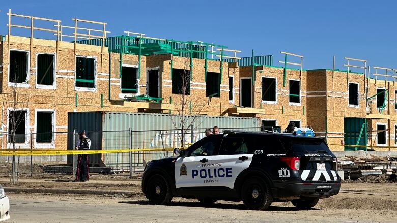 A marked Edmonton police cruiser parked in front of a residential building under construction.