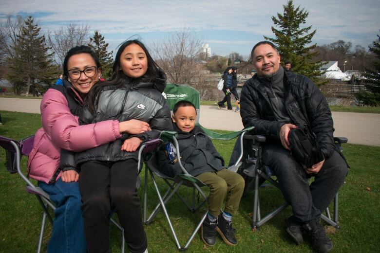 A family sitting in foldable chairs sit and smile.