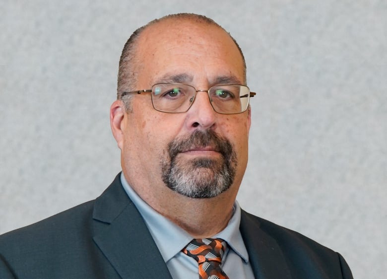 A man wearing a blue suit and glasses